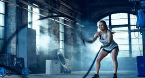 image shows a woman exercising in a weight room with ropes